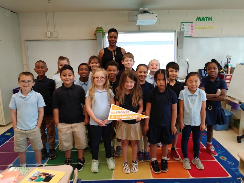 Smith Elementary School students post with 'Bronze Champions' pennant flag 